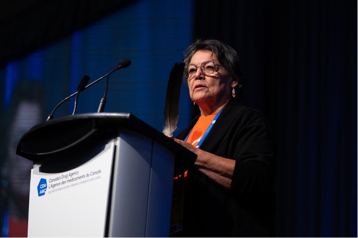 L’aînée Jenny Tenasco parlant au podium pendant l’ouverture officielle